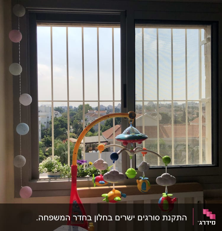 חלון עם סורגים ומובייל צבעוני לתינוק